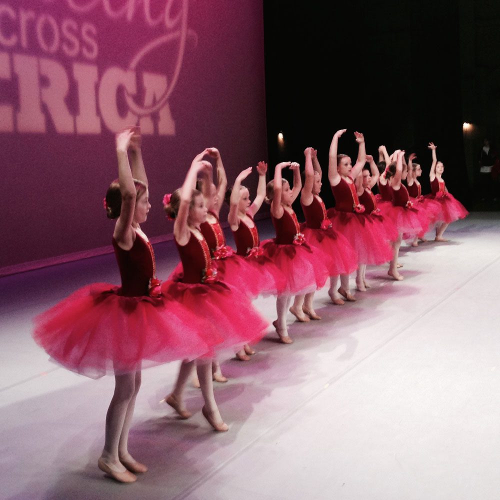 A group of young dancers in red tutus on stage.