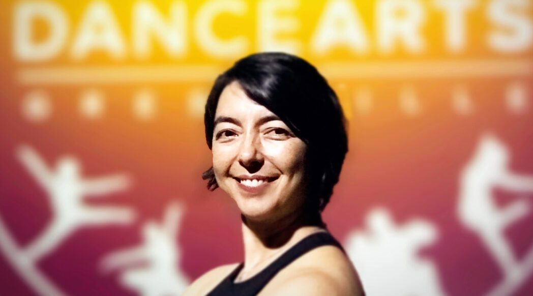 A woman standing in front of the dancearts logo.