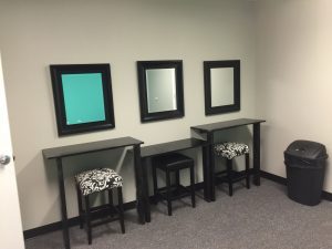 Three mirrors and stools in a small office.