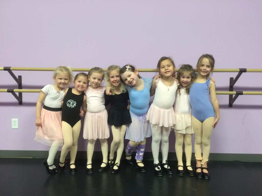 A group of young girls posing for a photo in a dance studio.