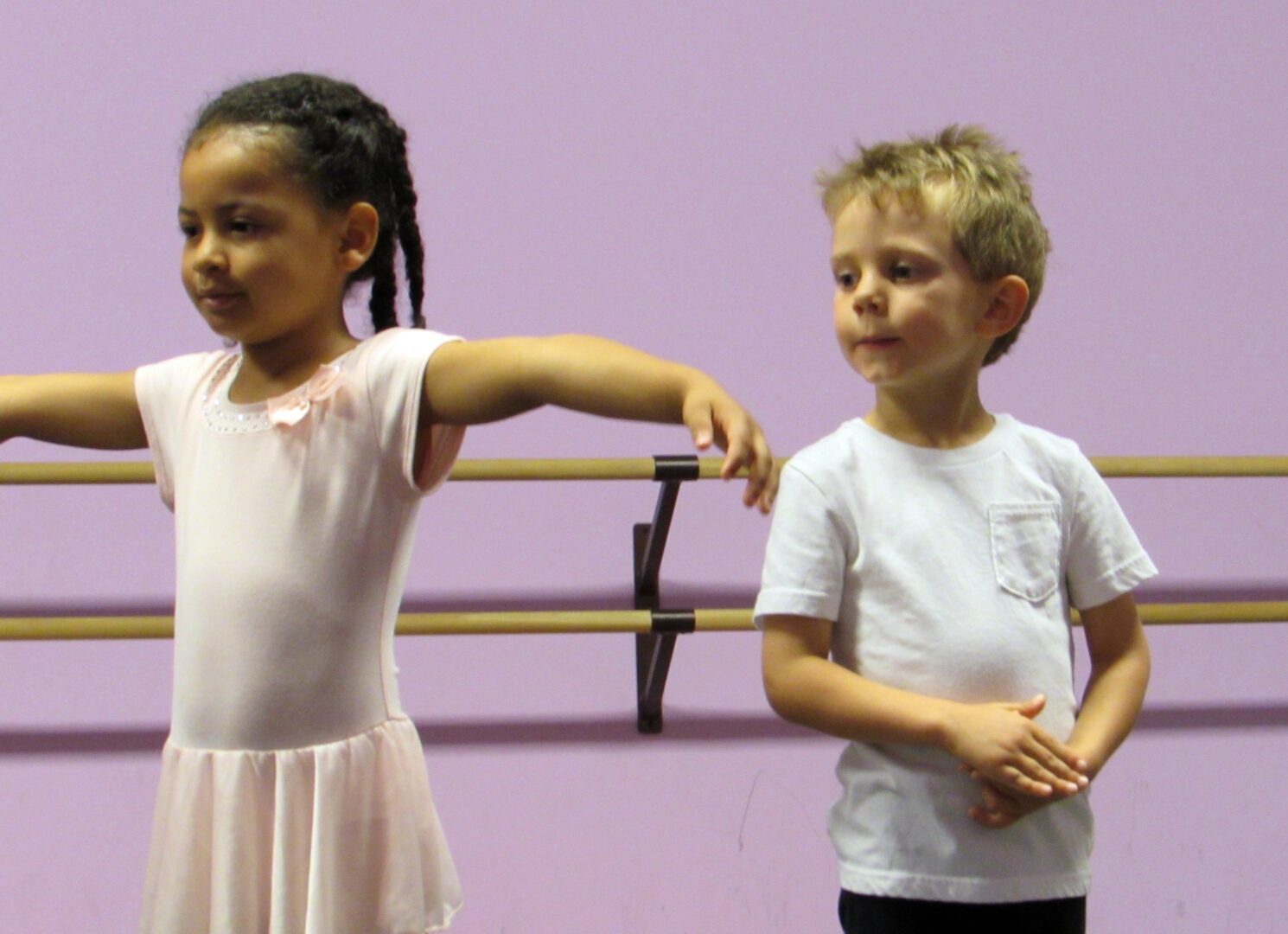 Two young children standing in a ballet class.