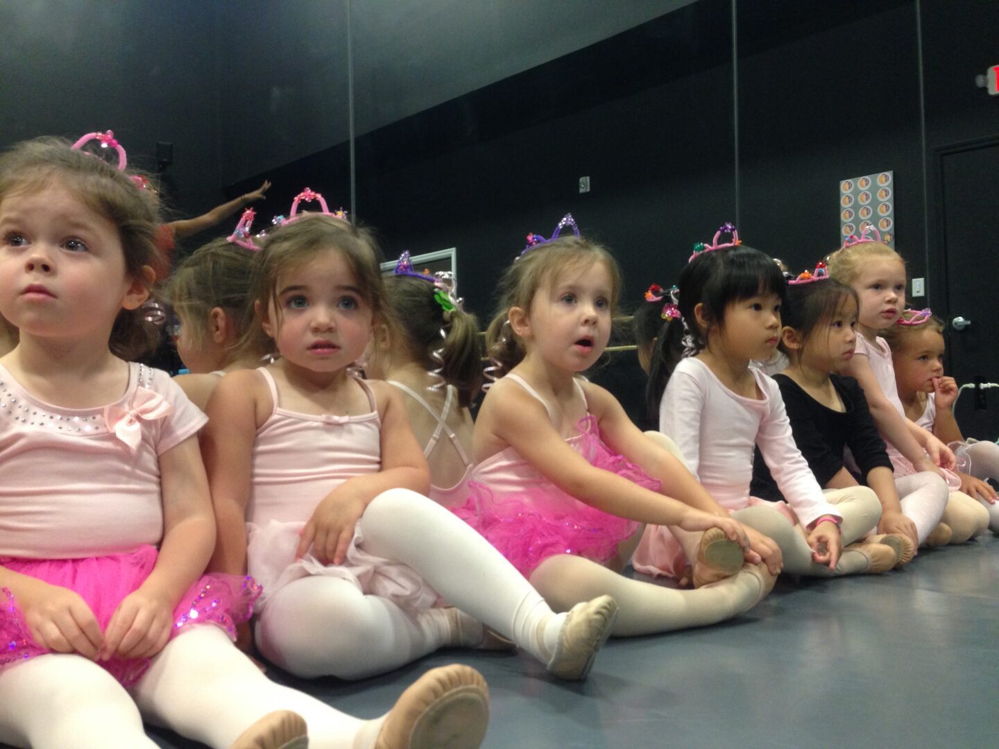 A group of young girls sitting in a ballet class.