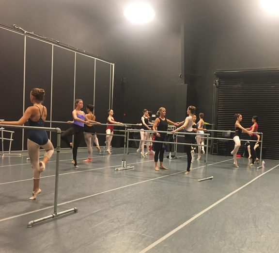 A group of dancers are practicing in a dance studio.