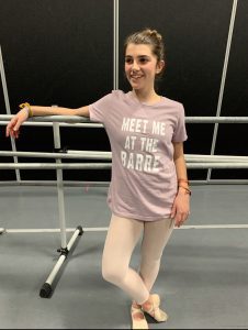 A girl wearing a t - shirt that says meet me at the barre.