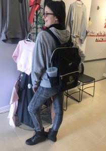 A girl standing in front of a rack of clothes.