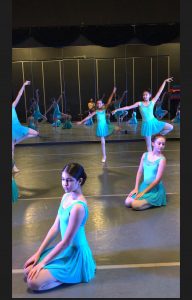 A group of young dancers practicing in a dance studio.