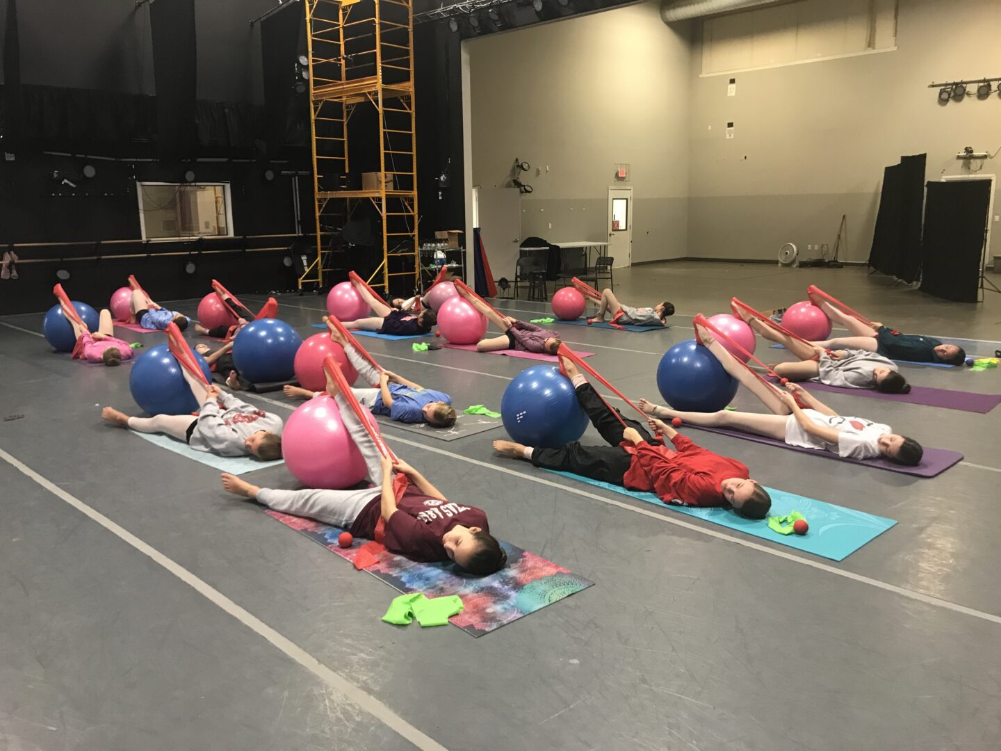 A group of people laying on mats in a gym.